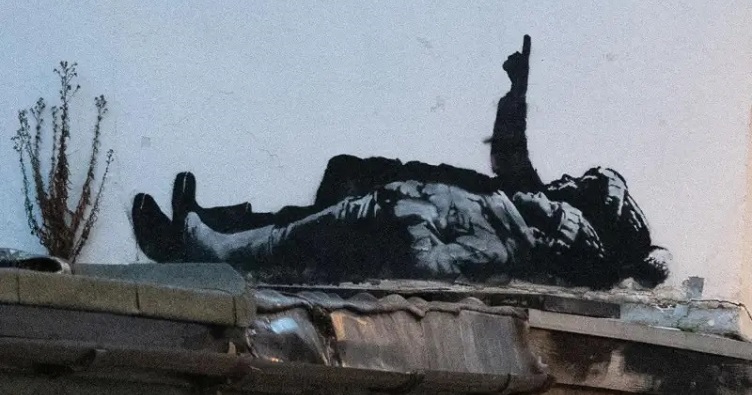 На граффити изображены два ребенка в резиновых сапогах, куртках и шапочках с помпонами. Один из них показывает рукой вверх. Фото: Banksy.