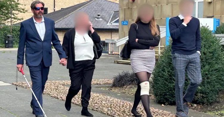 Навіть пересуваючись вулицями пішки, Ентоні Холл (крайній ліворуч) користується паличкою і спирається на руку партнерки. Фото: Julia Bryson/BBC